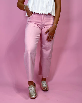 Person wearing pink pants and a white top on a pink background