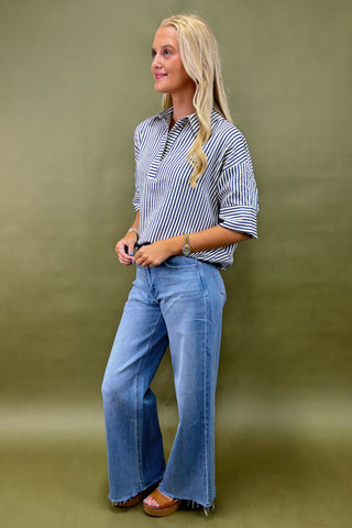 Woman wearing a striped shirt and blue jeans against a green background