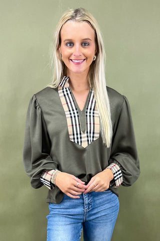 Woman wearing a green blouse with plaid accents against a green background