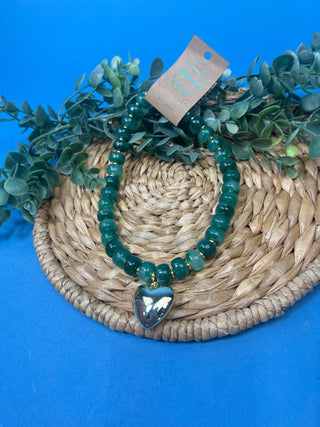 Green marbled resin bead necklace with polished gold heart pendant, gold-tone spacer accents, adjustable cord closure, and lightweight statement design available in multiple colors.