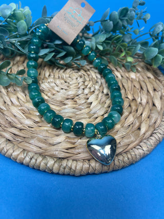 Green marbled resin bead necklace with polished gold heart pendant, gold-tone spacer accents, adjustable cord closure, and lightweight statement design available in multiple colors.