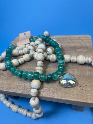 Green marbled resin bead necklace with polished gold heart pendant, gold-tone spacer accents, adjustable cord closure, and lightweight statement design available in multiple colors.
