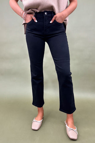 Person wearing black jeans and a beige top on a green background