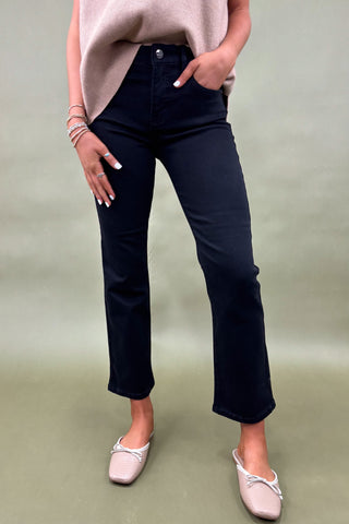 Person wearing black jeans and light pink shoes on a plain background