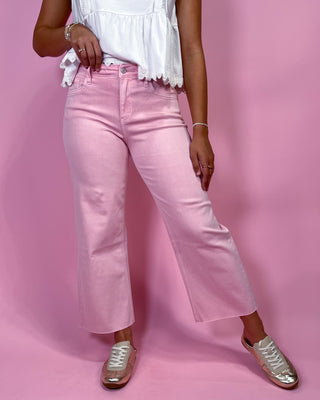 Person wearing pink jeans and a white top on a pink background