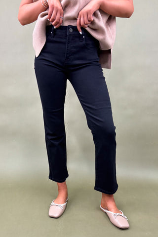 Person wearing navy blue jeans and a light pink top on a plain background
