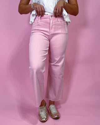 Person wearing light pink jeans against a pink background