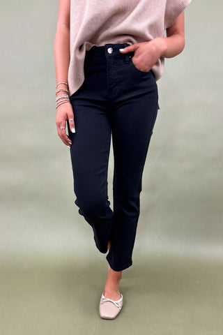 Person wearing black pants and a light pink top on a plain background