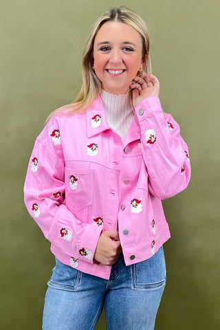 Person wearing a pink jacket with embroidered designs on a green background