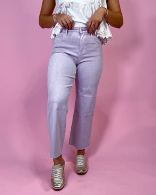 Person wearing light purple jeans and a white top on a pink background