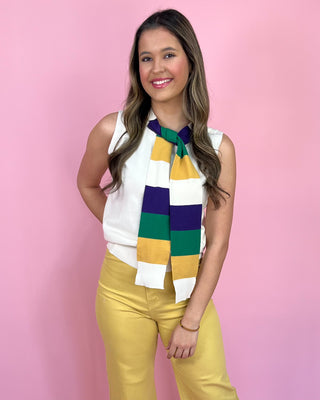 Woman wearing a colorful scarf and yellow pants against a pink background