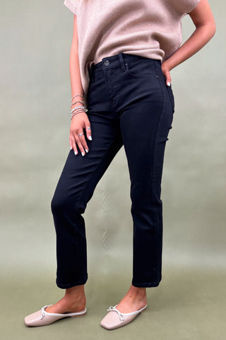 Person wearing black pants and a light pink top on a plain background