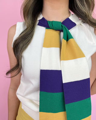 Person wearing a colorful striped scarf against a pink background