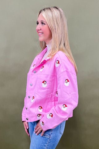Woman wearing a pink jacket with character patches against a beige background