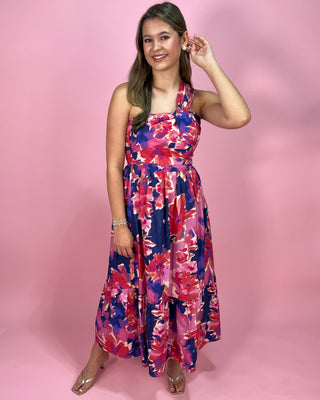 Woman wearing a colorful floral dress against a pink background
