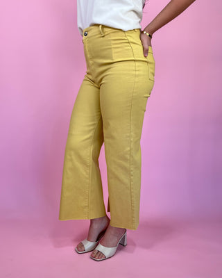 Person wearing yellow pants on a pink background