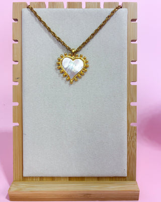 Woman wearing a gold necklace with a heart-shaped pendant on a white background