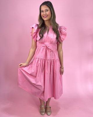Woman wearing a pink dress against a pink background