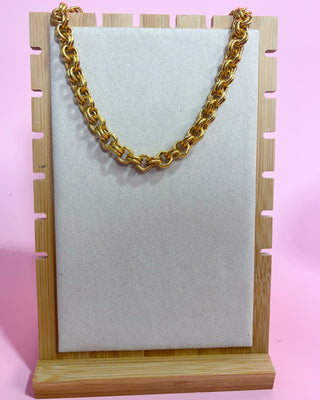 Gold chain on a wooden stand with a pink background