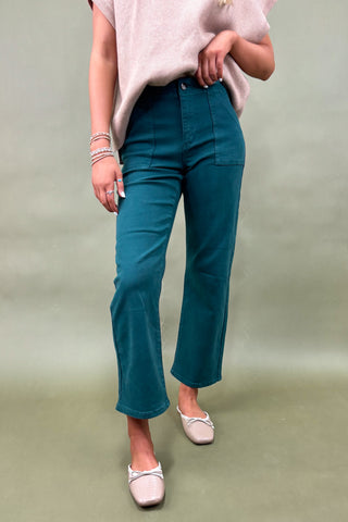 Person wearing teal pants and a light pink top on a plain background
