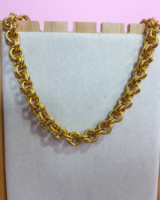 Gold chain necklace on a light pink background