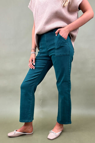 Person wearing teal pants and a pink top against a plain background