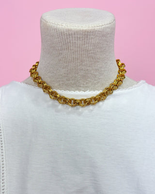Gold chain necklace on a mannequin with a pink background