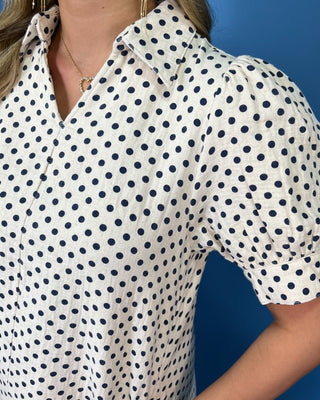 Woman modeling an ivory polka dot puff sleeve mini dress with a button-front design.