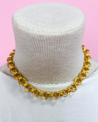 Gold chain necklace on a mannequin with a pink background