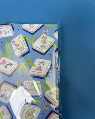 Package of Mahjong Guest Napkins featuring colorful Mahjong tile illustrations with bamboo leaves on a soft blue background. Premium 3-ply paper guest towels for entertaining and game nights.