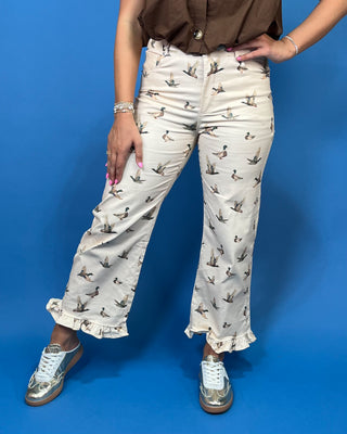 A person wearing cream-colored cropped pants with a brown duck print, styled with a brown top