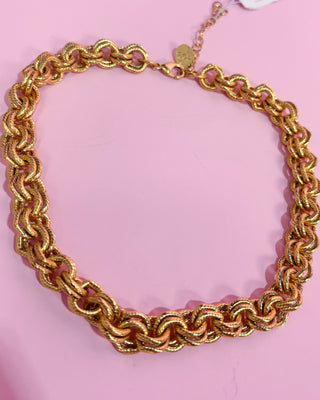 Gold chain necklace on a pink background