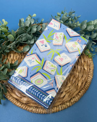 Package of Mahjong Guest Napkins featuring colorful Mahjong tile illustrations with bamboo leaves on a soft blue background. Premium 3-ply paper guest towels for entertaining and game nights.