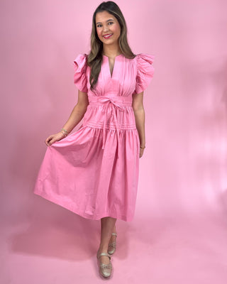 Woman wearing a pink dress against a pink background