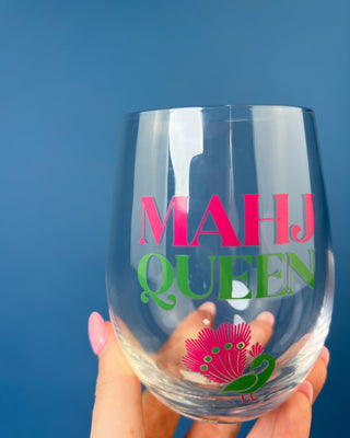 Mahj Queen stemless wine glass with vibrant pink and green lettering and a colorful peacock design on clear glass, perfect for Mahjong game nights and entertaining.