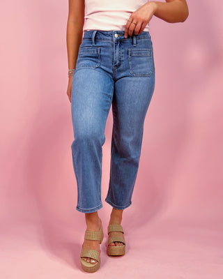 Person wearing blue jeans on a pink background