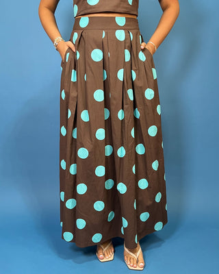 Woman modeling a brown and turquoise polka dot puff sleeve crop top with a matching pleated maxi skirt.