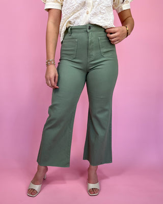 Person wearing green pants against a pink background