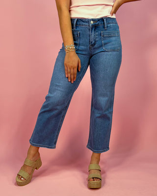 Person wearing blue jeans and sandals on a pink background