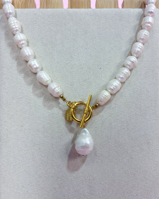 Pearl necklace with a gold clasp on a light gray background