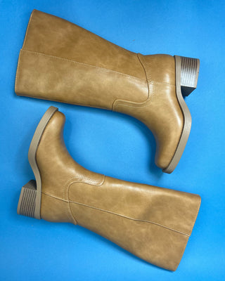 A pair of knee-high taupe faux-leather boots with a low block heel, shown against a solid blue background.
