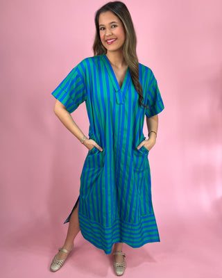 Woman wearing a blue and green striped dress against a pink background