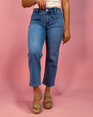 Person wearing blue jeans on a pink background
