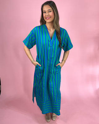 Woman wearing a blue and green striped dress against a pink background