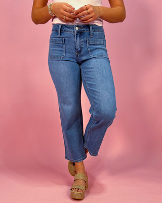 Person wearing blue jeans on a pink background