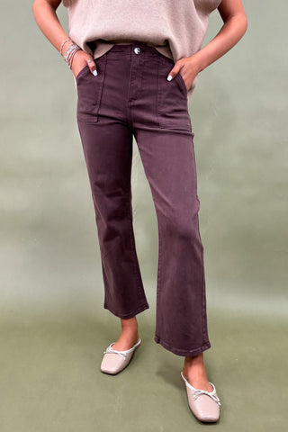 Person wearing purple pants and a beige top on a green background