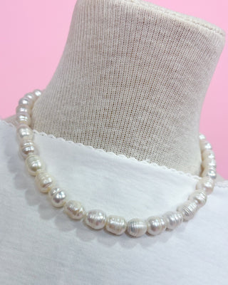 Pearl necklace on a mannequin with a pink background