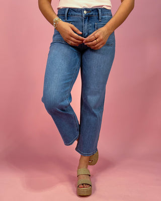 Person wearing blue jeans on a pink background
