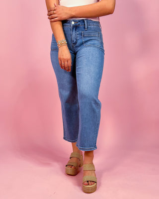 Person wearing blue jeans and platform sandals on a pink background