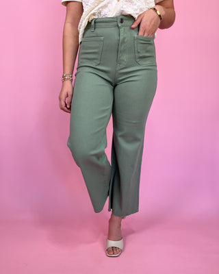 Person wearing green pants against a pink background
